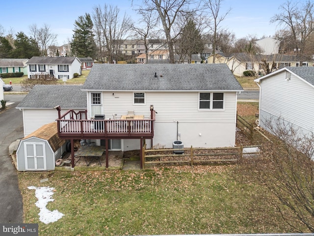 back of property with a wooden deck, a yard, and a shed