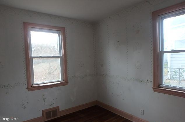 spare room with a wealth of natural light and dark hardwood / wood-style floors