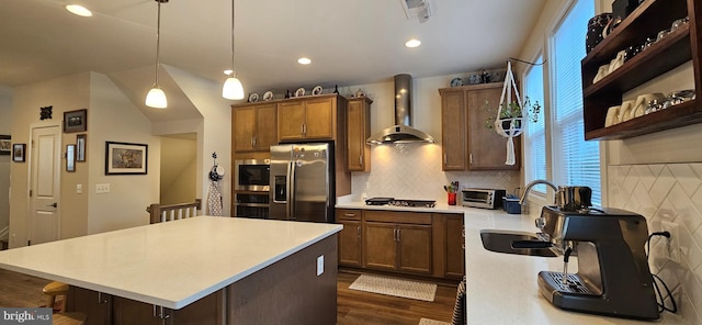 kitchen with decorative light fixtures, sink, backsplash, stainless steel appliances, and wall chimney exhaust hood