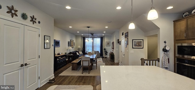 kitchen featuring dark brown cabinets, stainless steel microwave, dark hardwood / wood-style flooring, pendant lighting, and oven