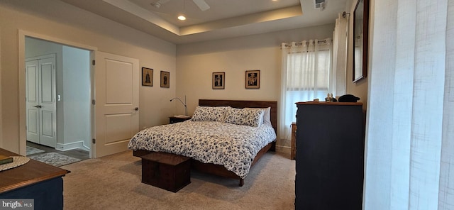 carpeted bedroom with a raised ceiling and ceiling fan