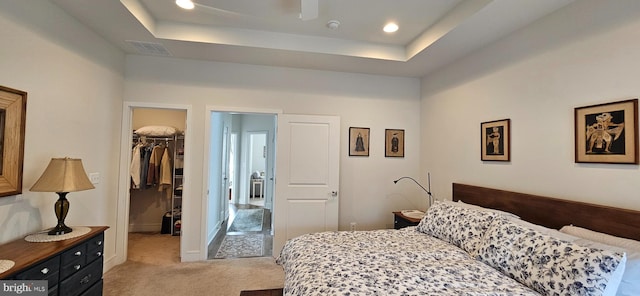 carpeted bedroom featuring a closet, a spacious closet, and a tray ceiling