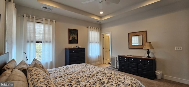 bedroom featuring light colored carpet, a raised ceiling, and ceiling fan