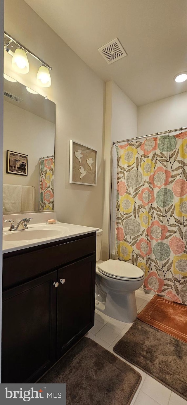 bathroom with tile patterned flooring, vanity, walk in shower, and toilet