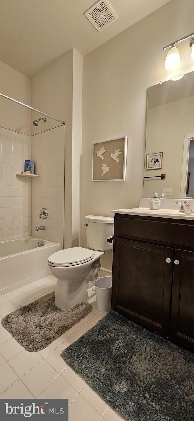 full bathroom with tile patterned flooring, vanity, tiled shower / bath combo, and toilet