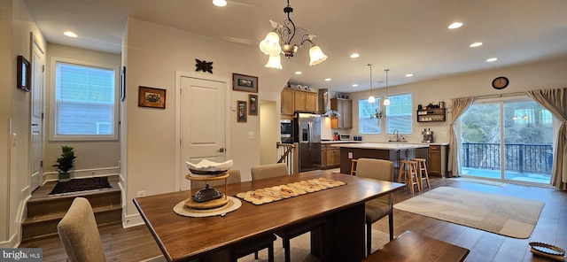 dining area with dark wood-type flooring, sink, and a notable chandelier