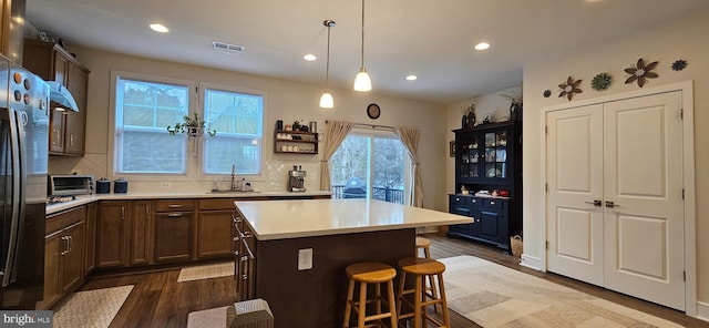 kitchen featuring sink, tasteful backsplash, decorative light fixtures, dark hardwood / wood-style floors, and a kitchen island