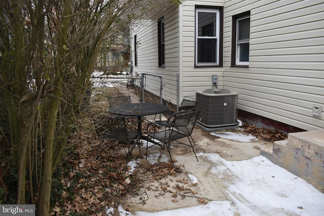 snow covered patio featuring central AC unit