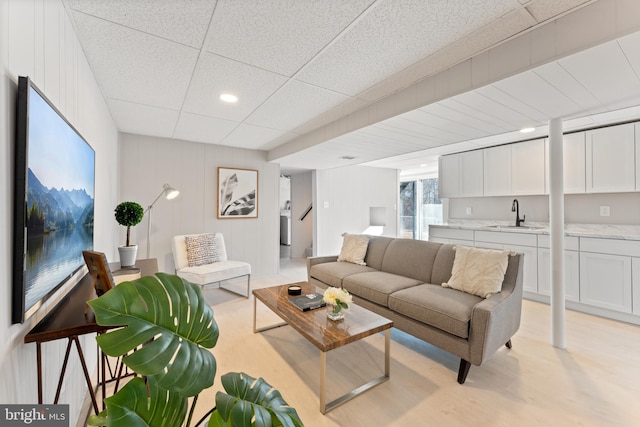 living room featuring sink, a paneled ceiling, and light hardwood / wood-style floors