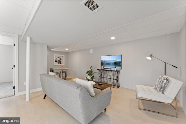 living room with a drop ceiling and light hardwood / wood-style flooring