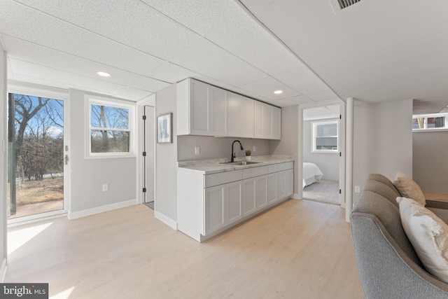 kitchen featuring white cabinetry, a paneled ceiling, sink, and light hardwood / wood-style flooring