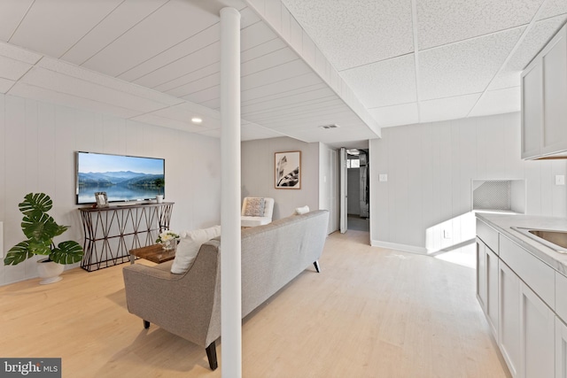 living room featuring a paneled ceiling and light hardwood / wood-style floors