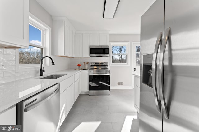 kitchen featuring light stone countertops, appliances with stainless steel finishes, sink, and white cabinets