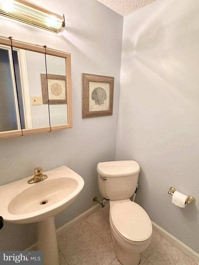 bathroom with sink, toilet, tile patterned flooring, and a textured ceiling