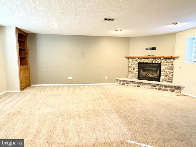 unfurnished living room with a stone fireplace, light colored carpet, and a textured ceiling