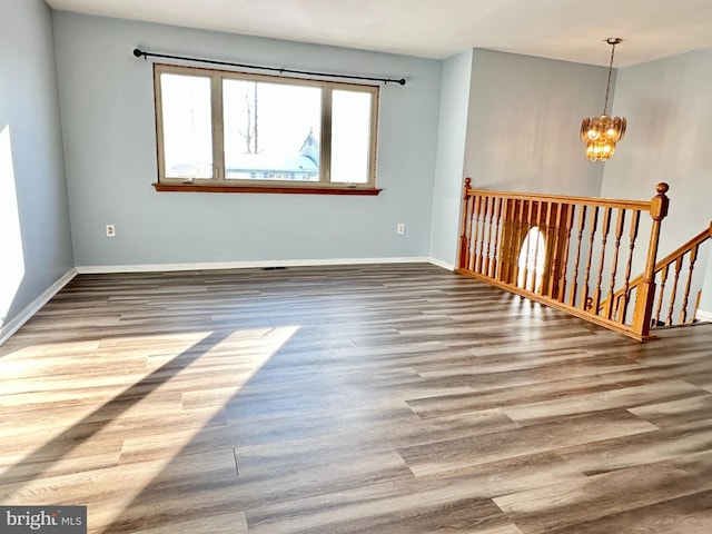 spare room featuring a notable chandelier and wood-type flooring