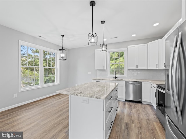 kitchen featuring stainless steel appliances, a kitchen island, sink, and white cabinets