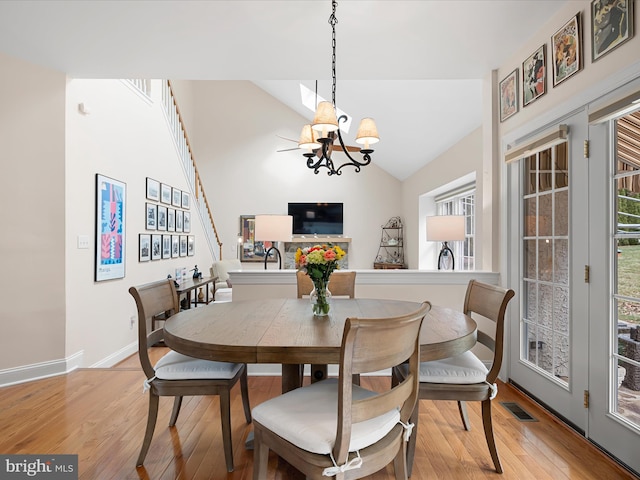 dining area featuring lofted ceiling, a chandelier, and light wood-type flooring