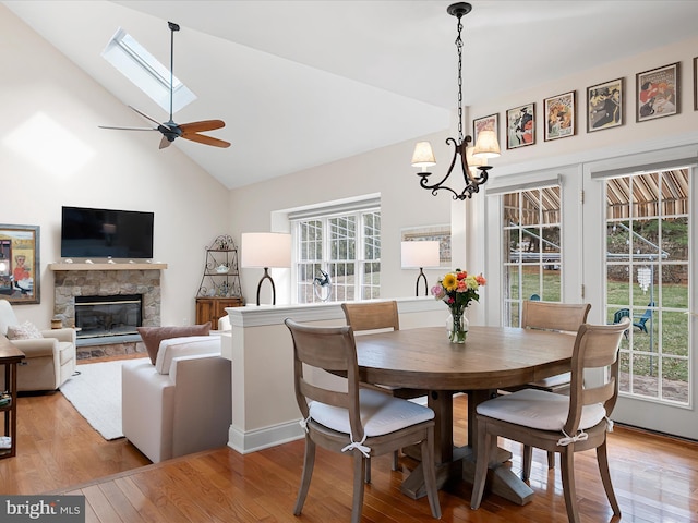 dining space with a fireplace, a wealth of natural light, a notable chandelier, and light wood-type flooring