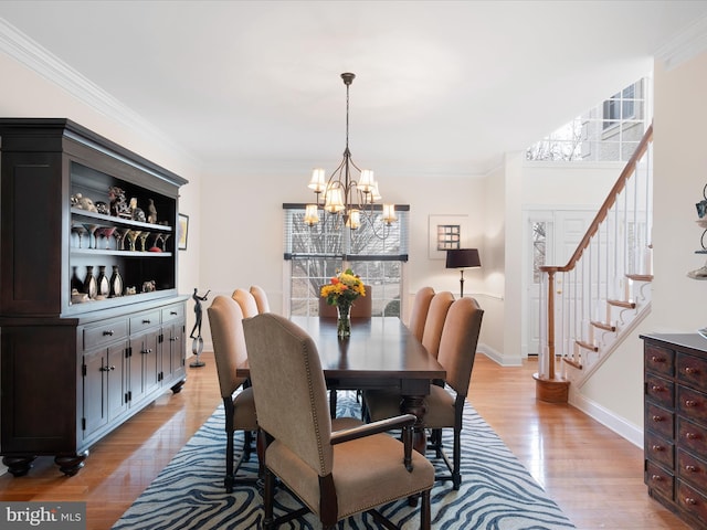 dining space with an inviting chandelier, light hardwood / wood-style flooring, and ornamental molding