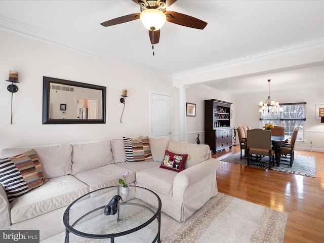 living room with crown molding, ceiling fan with notable chandelier, light hardwood / wood-style floors, and ornate columns