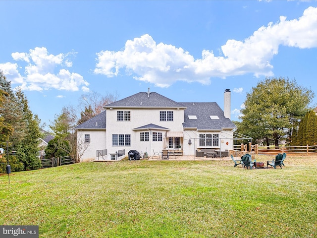 rear view of property featuring a yard and a fire pit