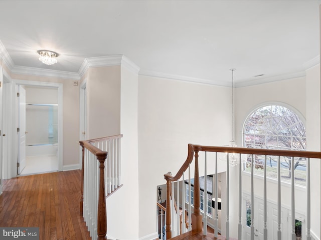 hall featuring wood-type flooring, ornamental molding, and a notable chandelier