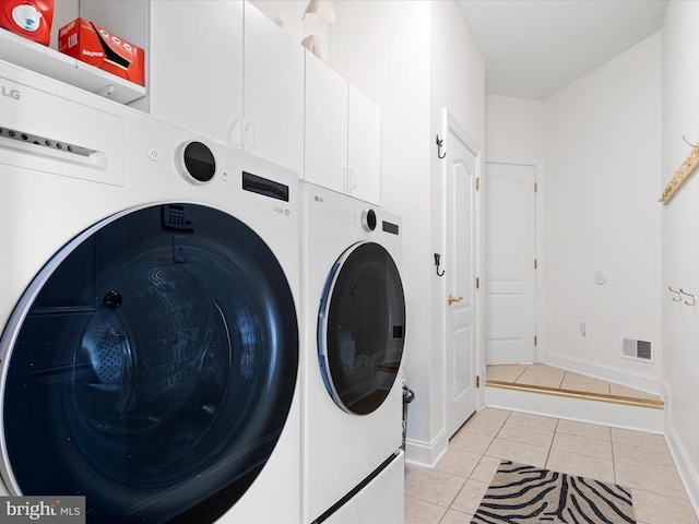 laundry room with separate washer and dryer, light tile patterned floors, and cabinets