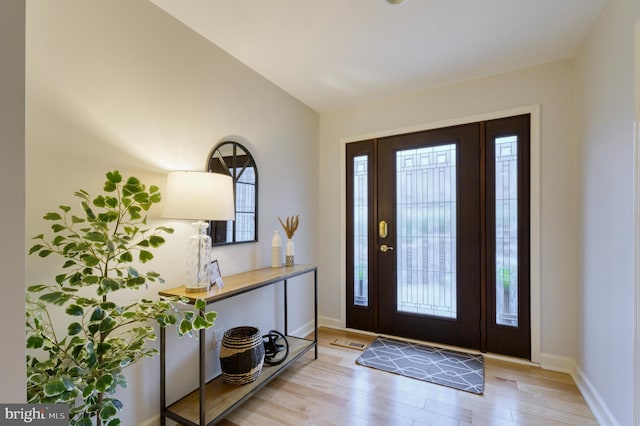 foyer entrance featuring lofted ceiling, a healthy amount of sunlight, and light hardwood / wood-style floors