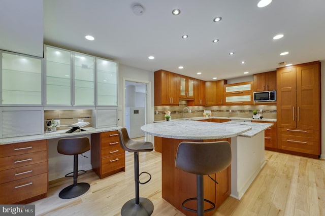 kitchen with tasteful backsplash, a kitchen breakfast bar, light stone counters, and light wood-type flooring