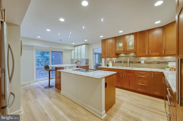 kitchen featuring stainless steel refrigerator, a kitchen breakfast bar, a center island, and light hardwood / wood-style flooring