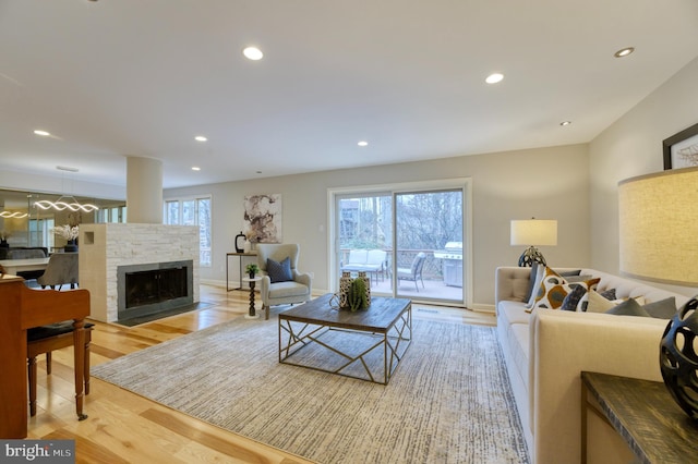 living room featuring a fireplace, light hardwood / wood-style floors, and a healthy amount of sunlight