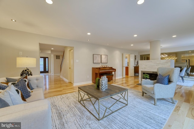 living room with a multi sided fireplace and light wood-type flooring