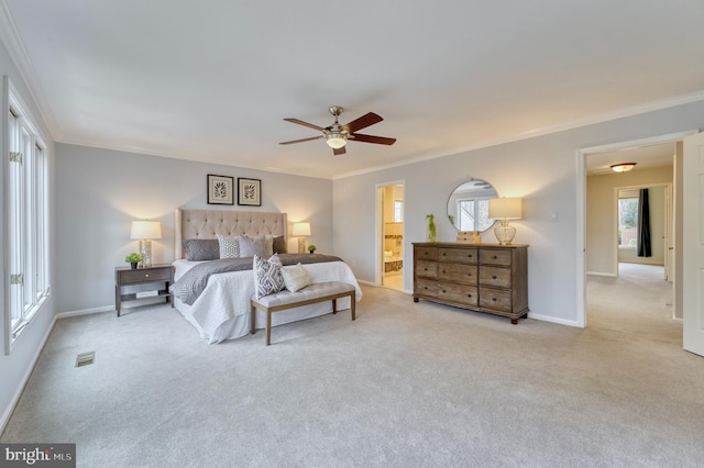 bedroom with ceiling fan, light colored carpet, ornamental molding, and ensuite bath