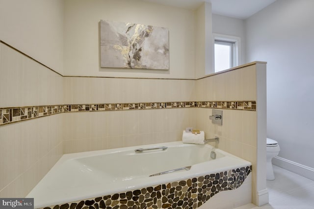 bathroom with a relaxing tiled tub, toilet, and tile walls