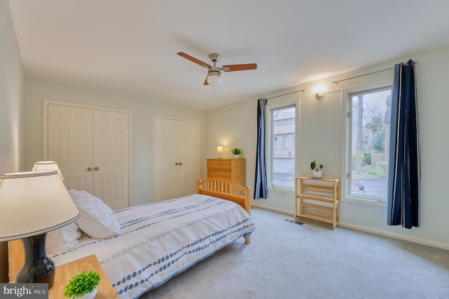 carpeted bedroom with two closets and ceiling fan