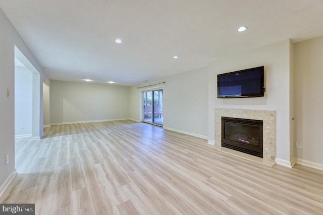 unfurnished living room featuring a high end fireplace and light hardwood / wood-style flooring