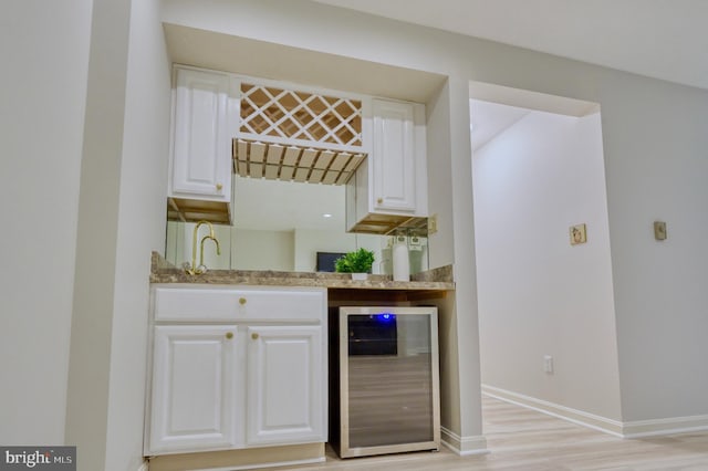 bar featuring white cabinetry, beverage cooler, and light wood-type flooring