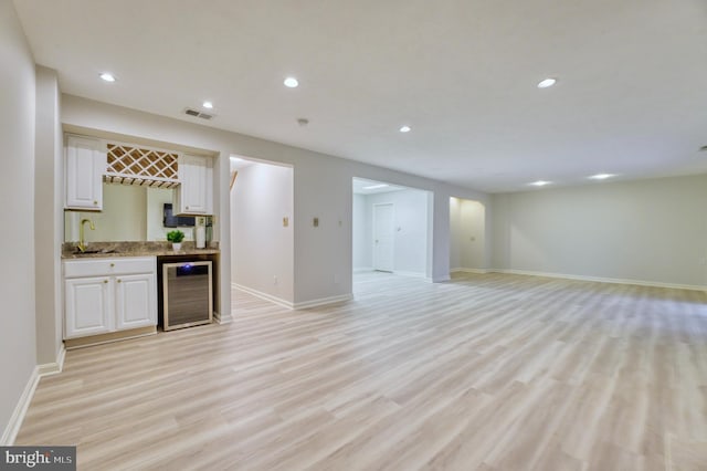 kitchen with white cabinets, sink, wine cooler, and light hardwood / wood-style floors