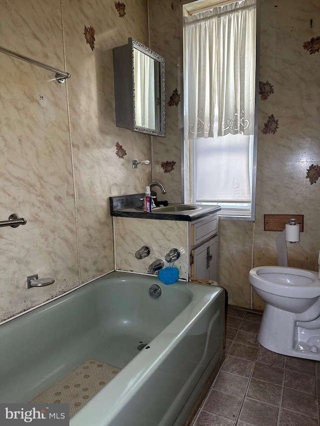 bathroom with vanity, toilet, and a tub