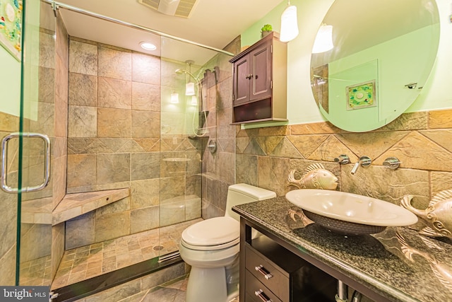 bathroom featuring vanity, a shower with shower door, tile walls, and toilet