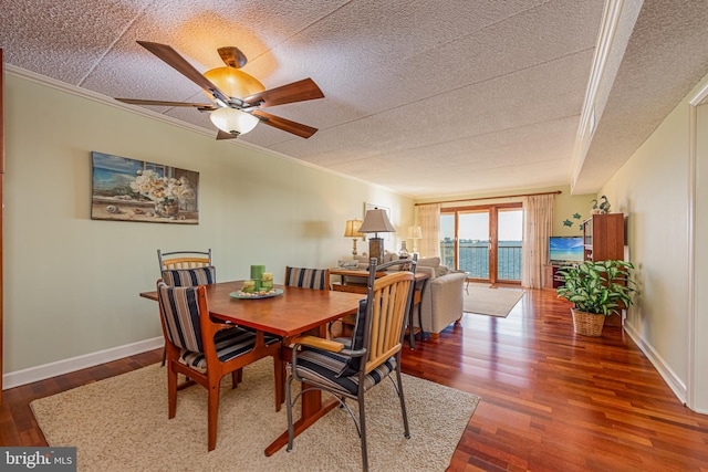 dining room with dark wood-type flooring, ceiling fan, ornamental molding, and a textured ceiling