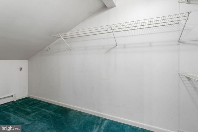 walk in closet featuring vaulted ceiling, baseboard heating, and dark colored carpet