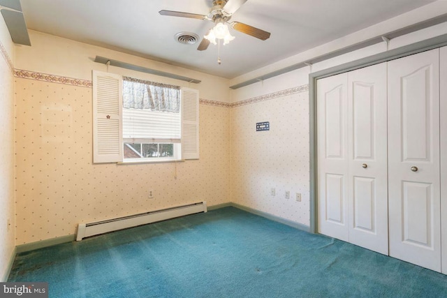 unfurnished bedroom featuring dark colored carpet, a baseboard heating unit, ceiling fan, and a closet