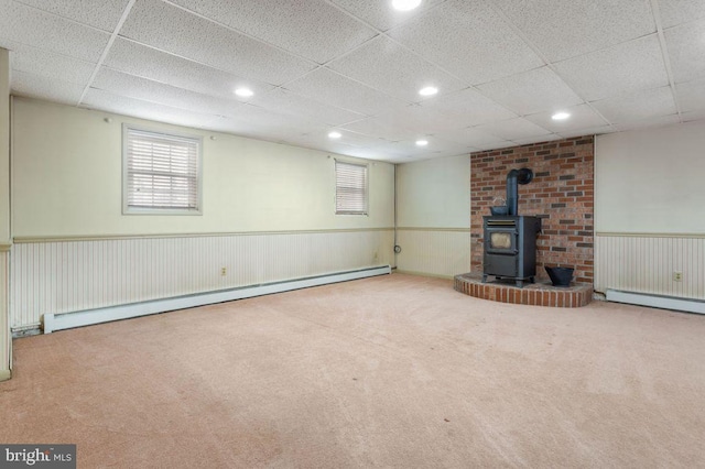 basement featuring a baseboard radiator, carpet floors, and a wood stove