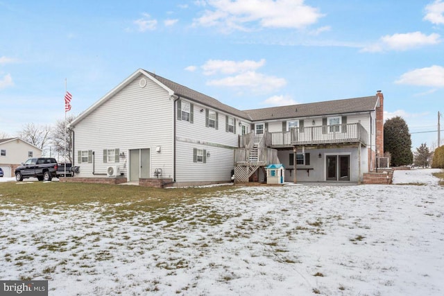 snow covered rear of property with a wooden deck