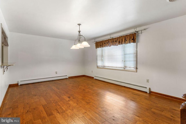 spare room with wood-type flooring, a baseboard heating unit, and a notable chandelier