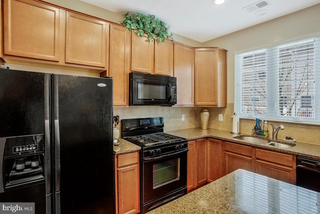 kitchen featuring tasteful backsplash, light stone countertops, sink, and black appliances