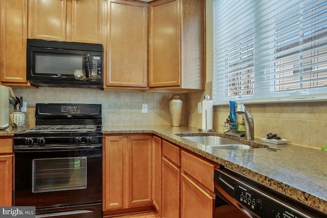 kitchen featuring tasteful backsplash, light stone countertops, sink, and black appliances