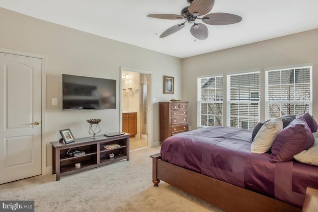 bedroom featuring ceiling fan, light colored carpet, and connected bathroom